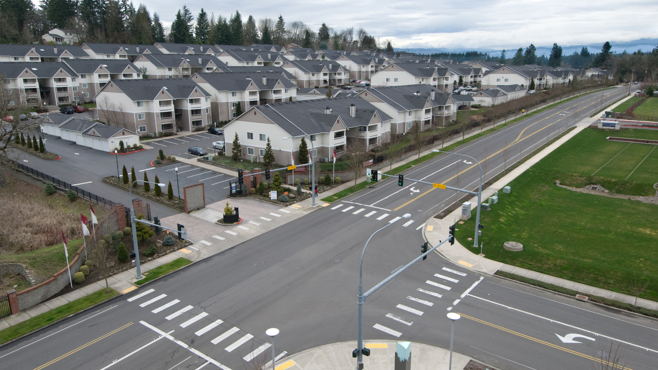 Aerial view of a signalized intersection with marked crosswalks beside a large apartment community.